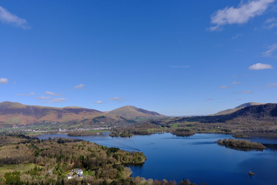 A breathtaking aerial view of Keswick, featuring Derwentwater, surrounding hills, and lush greenery.