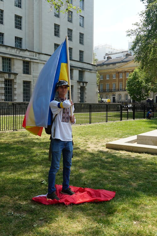 Man Standing in a Park and Holding Flags 