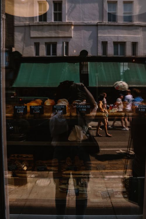 Free A city street reflection captures a patisserie window display and passersby. Stock Photo