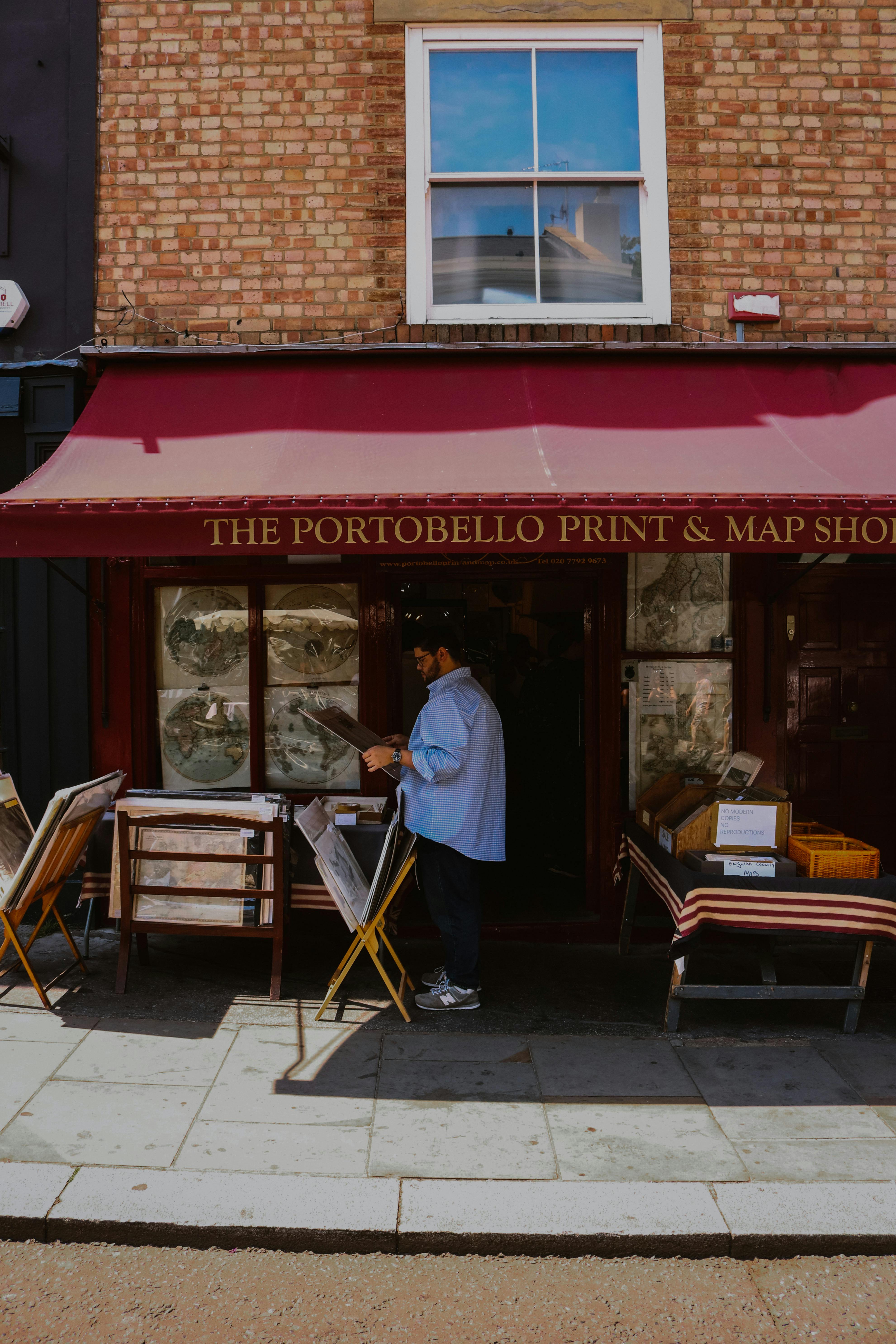 A man browsing prints outside The Portobello Print & Map Shop in a charming street setting.