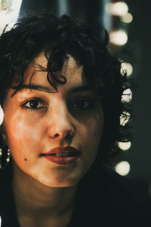 Free A thoughtful close-up portrait of a woman with curly hair and expressive eyes. Stock Photo