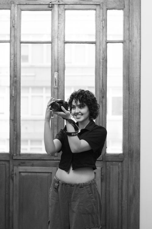 Free A woman confidently taking a photograph indoors with natural light. Stock Photo