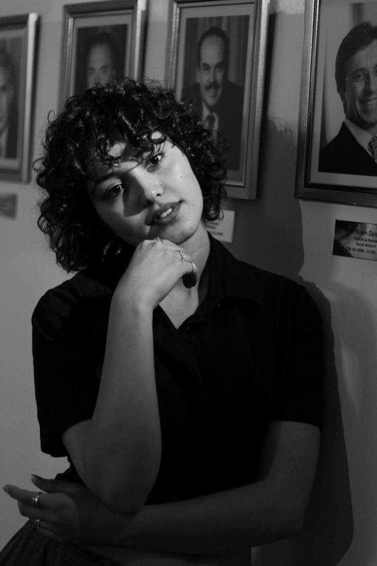 A Woman Posing Against A Wall Of Portraits