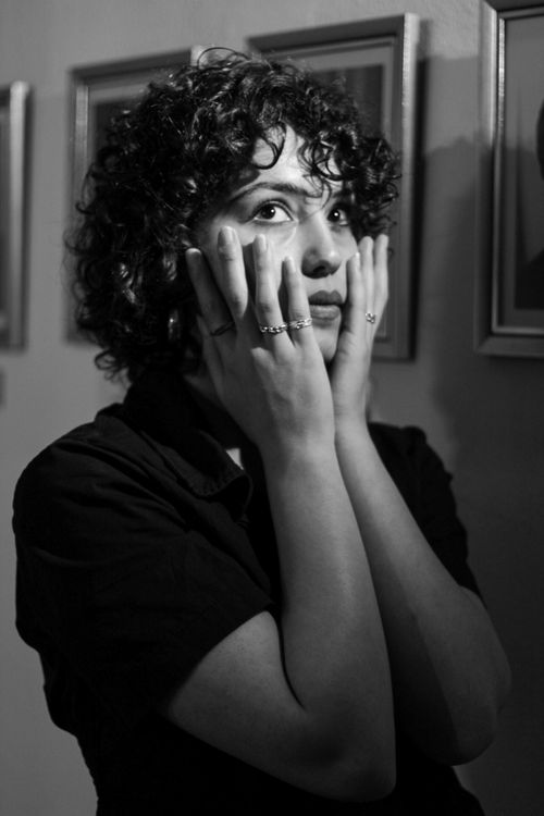 Free Black and white portrait of a woman with curly hair touching her face, showcasing emotion. Stock Photo