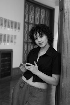 Chic black and white portrait of a young woman standing confidently in a doorway.
