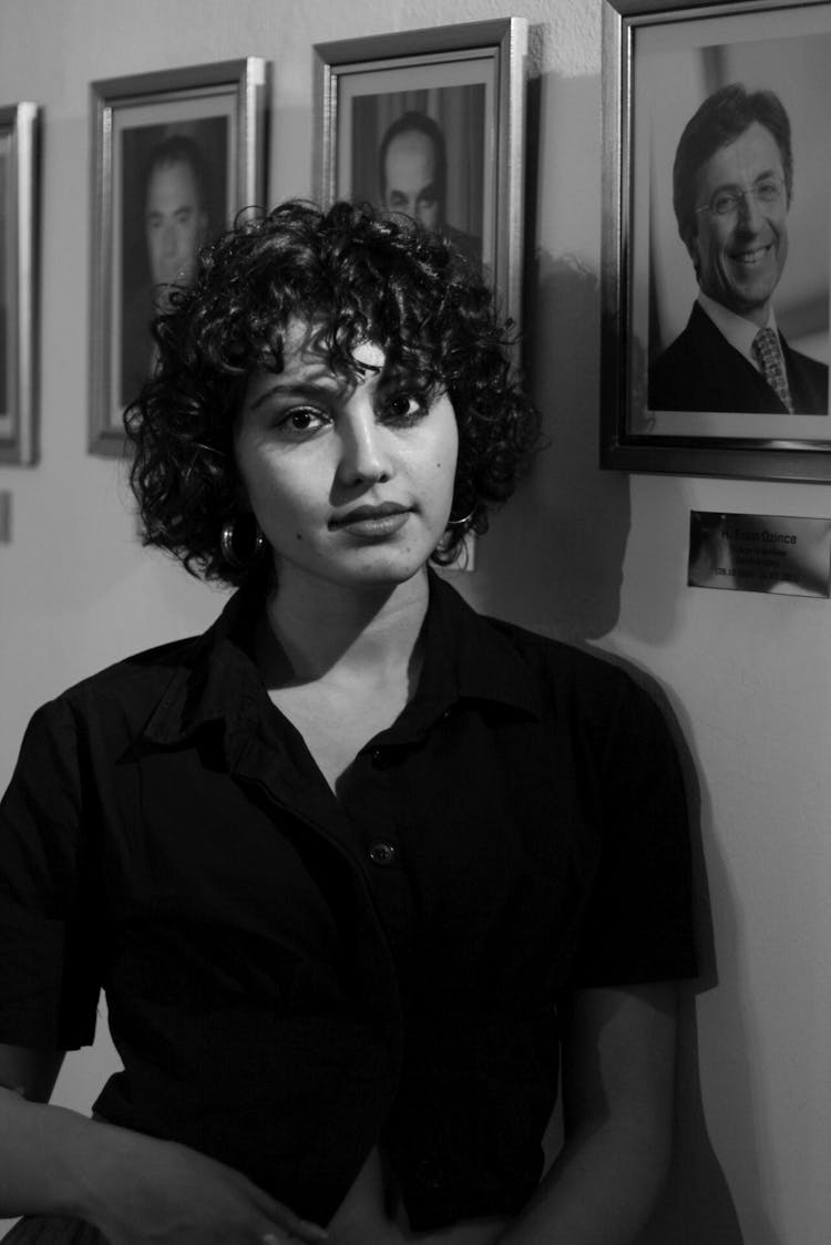 A Woman Posing Against Portraits Hanging On The Wall