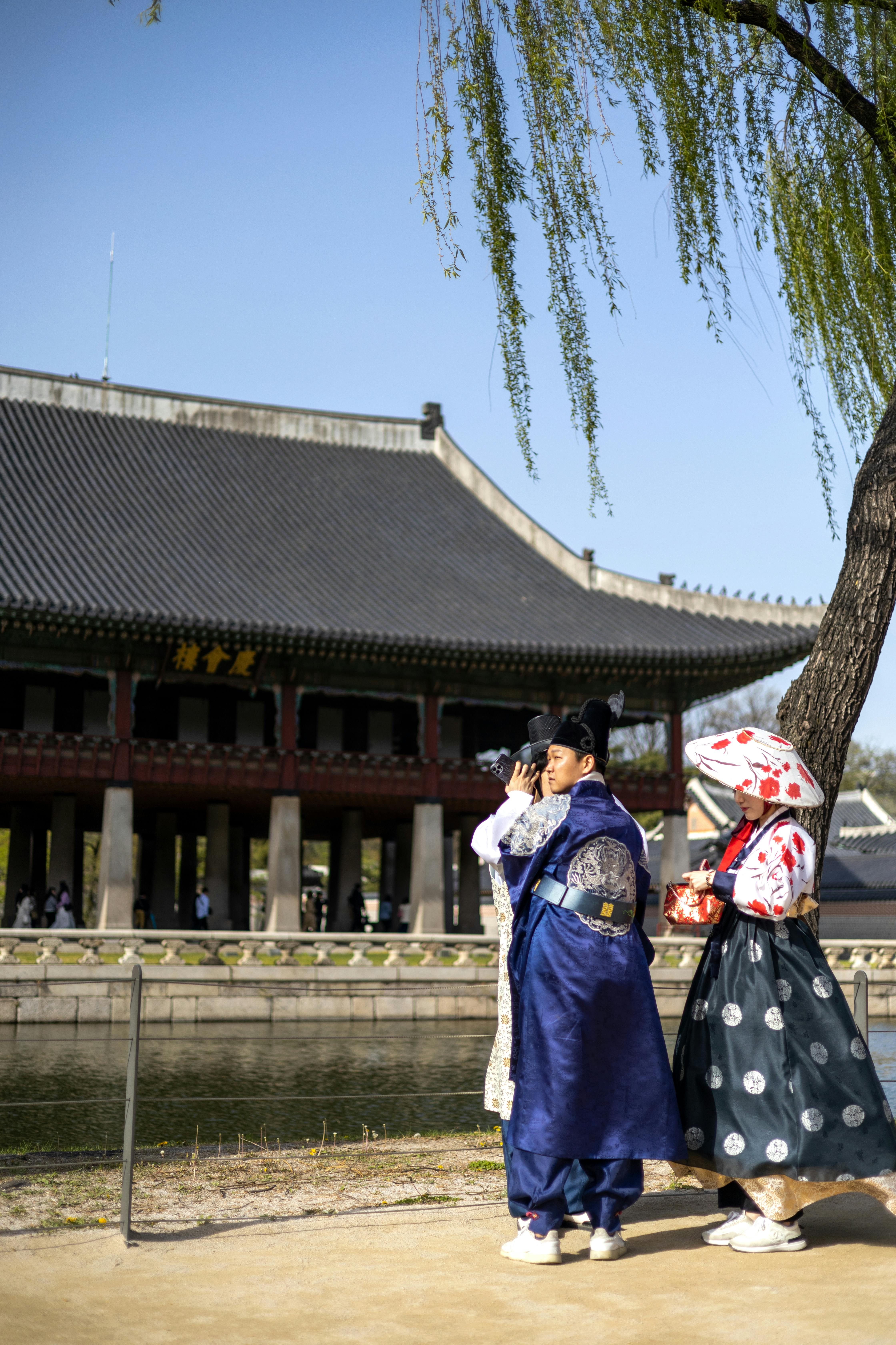 two women in traditional clothing standing near a pond