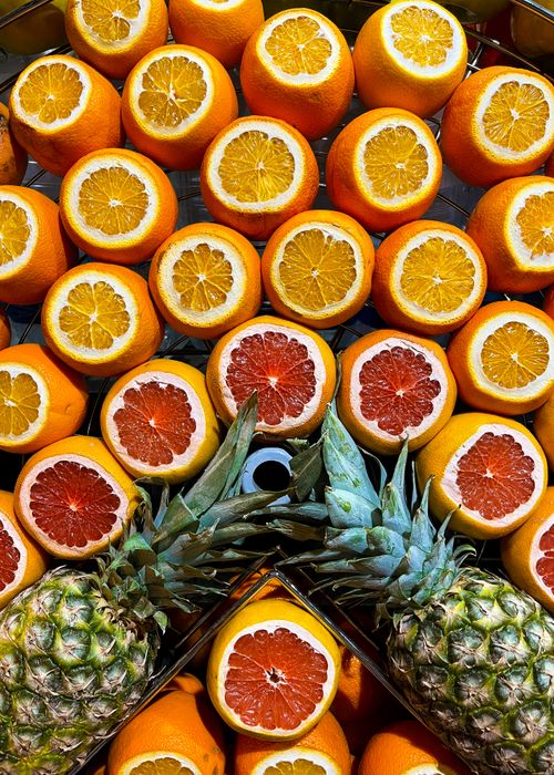 Free Colorful array of sliced oranges, grapefruits, and pineapples creating a vibrant fruit pattern. Stock Photo
