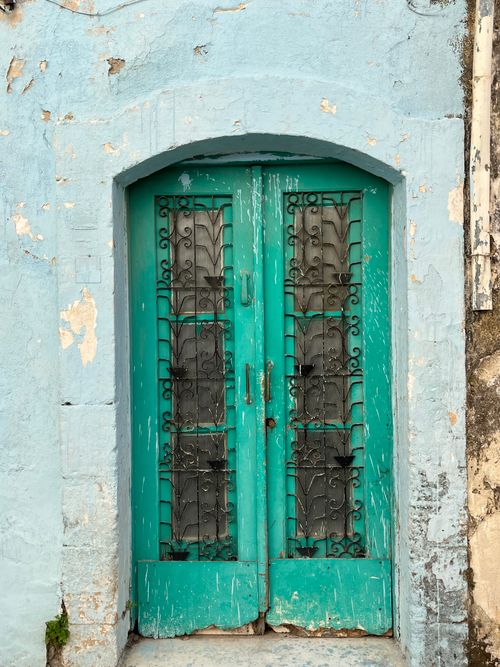 Free An aged turquoise door with intricate iron bars, showcasing vintage charm and weathered texture. Stock Photo