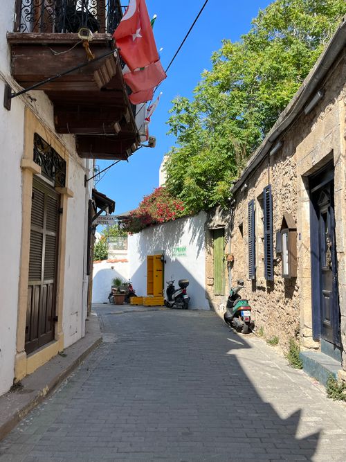 Free A narrow village street featuring traditional houses and Turkish flags on a sunny day. Stock Photo