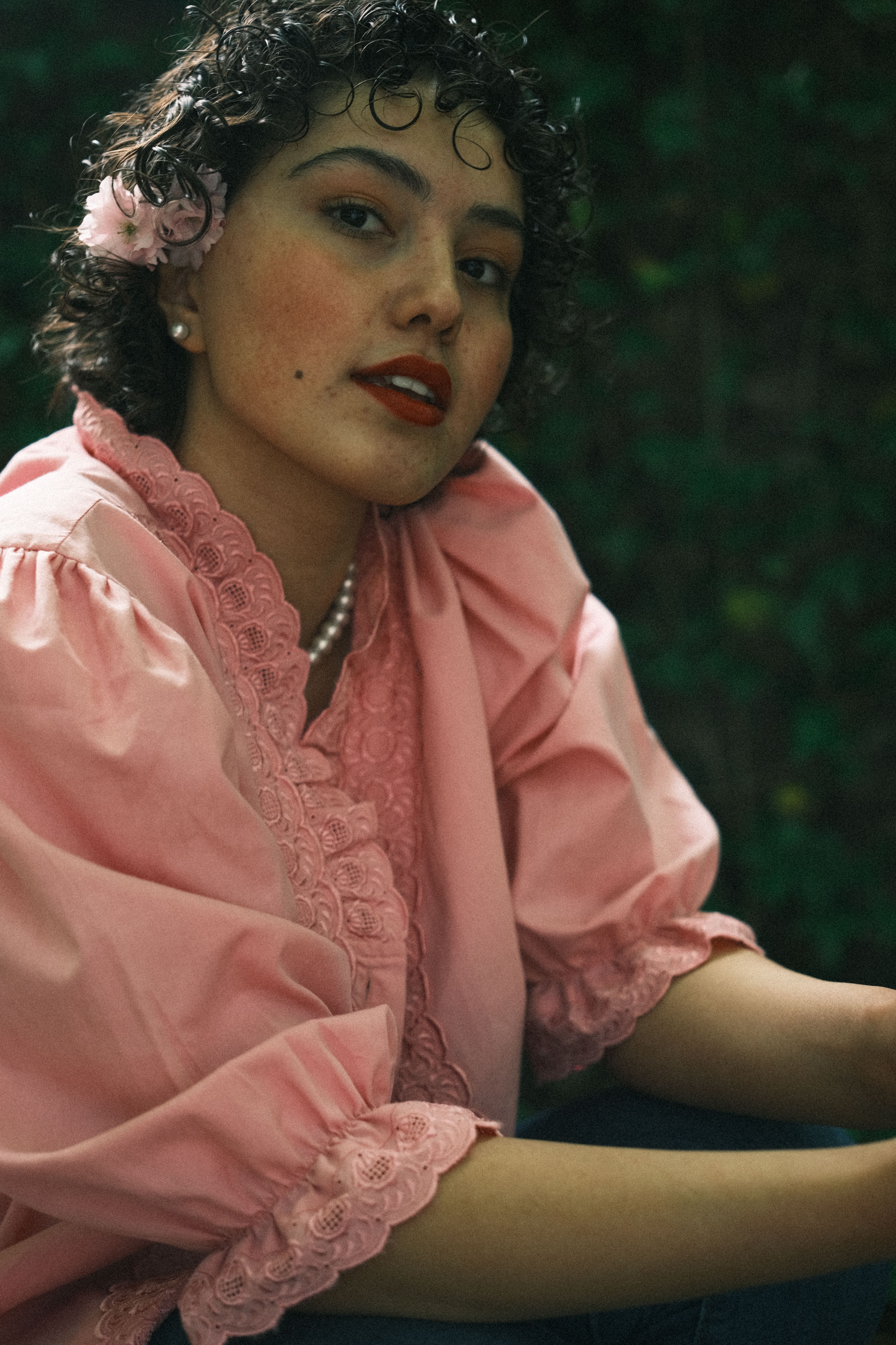 Portrait of a woman in a pink lace blouse with floral accents outdoors. Fashion and elegance.
