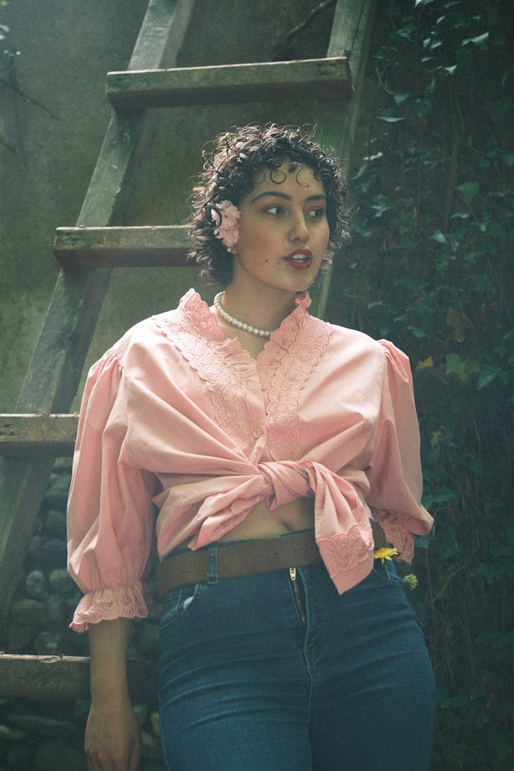 Woman In A Pink Blouse Leaning Against A Ladder