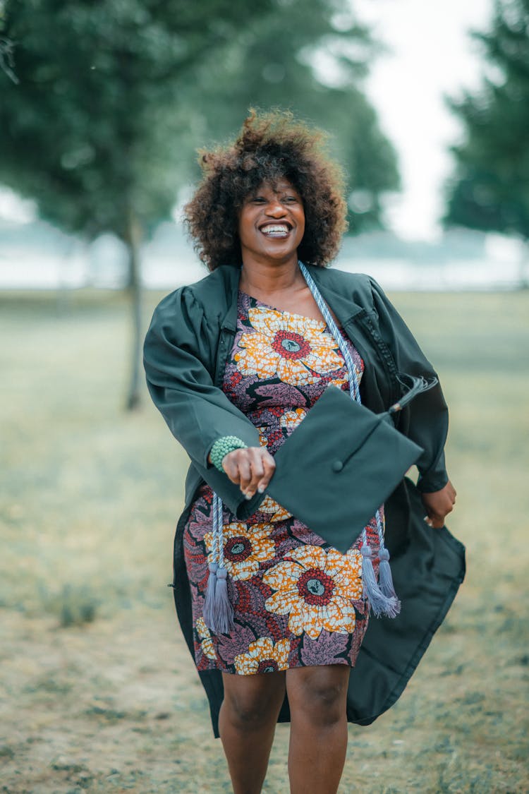 Smiling Graduate In Dress Holding Academic Hat