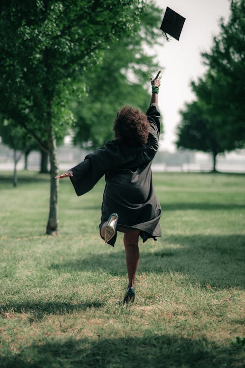 Woman in a Graduation Gown Throwing her Hat up in the Air 