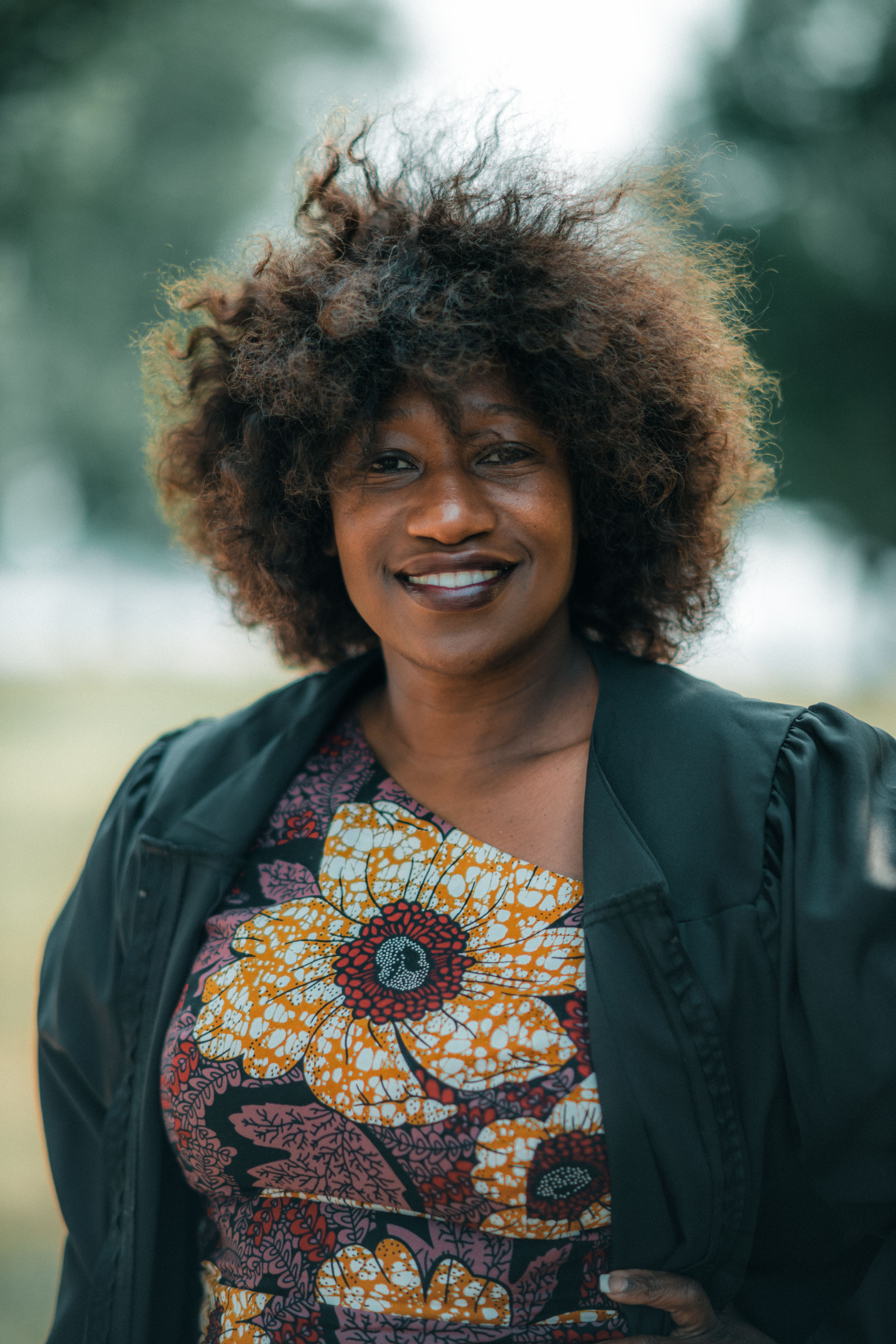 Elegant portrait of a woman with curly hair in a colorful dress, captured outdoors.