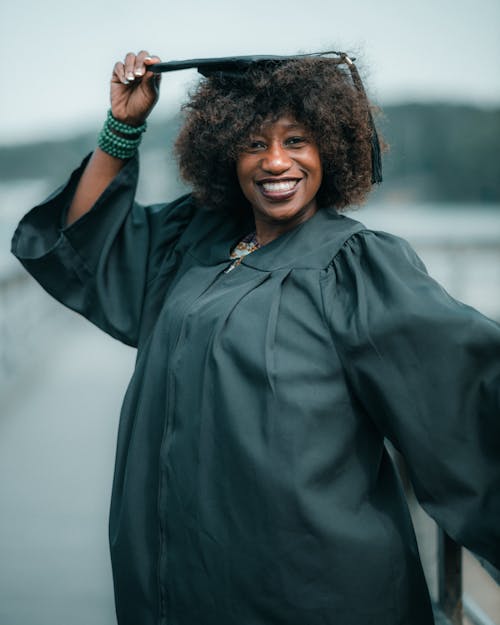 Photo of a Smiling Woman Wearing a Graduation Gown and Mortarboard