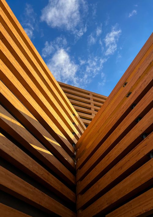 Free A stunning view of modern architectural design with wooden panels against a bright blue sky. Stock Photo