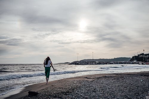 Barefoot Woman Walking along Sea on Beach