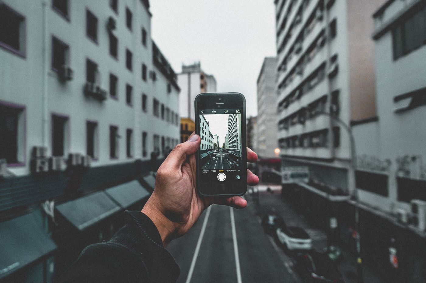 A person holding a smartphone while standing outdoors near a road