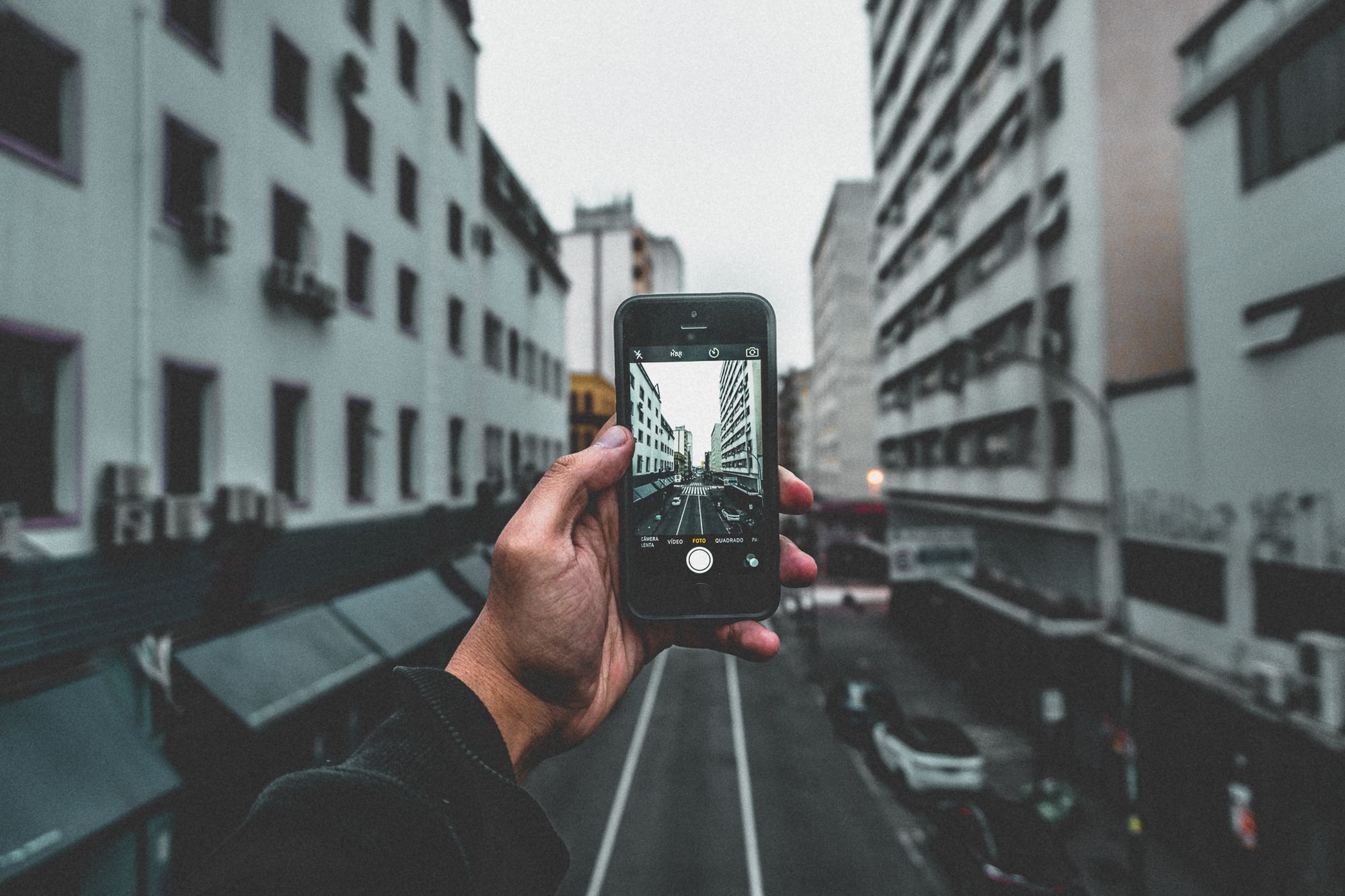 A city street view captured through a smartphone, highlighting urban architecture and perspective.