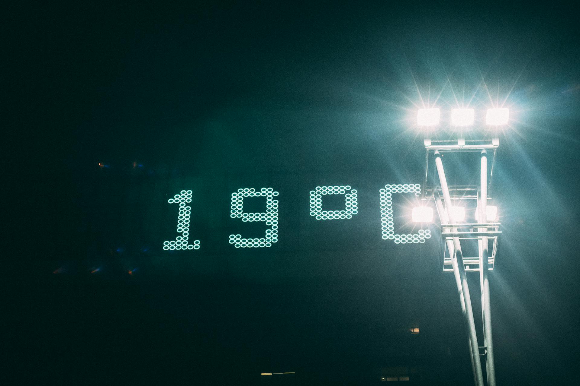 Bright digital temperature display showing 19°C under stadium floodlights at night.