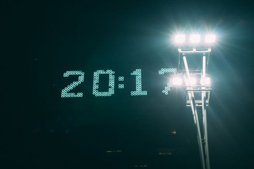 Illuminated digital clock and stadium lights creating a stunning visual contrast against the night sky.
