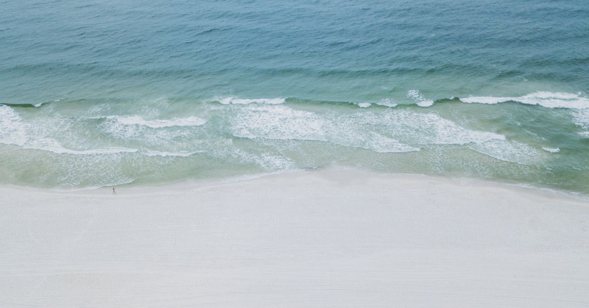 A serene aerial image showcasing the tranquil beaches and clear waters of Orange Beach, Alabama.