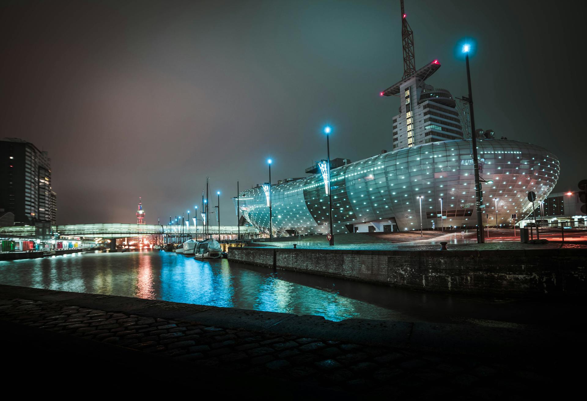 Night view of a modern building and waterfront with illuminated architecture and reflections.