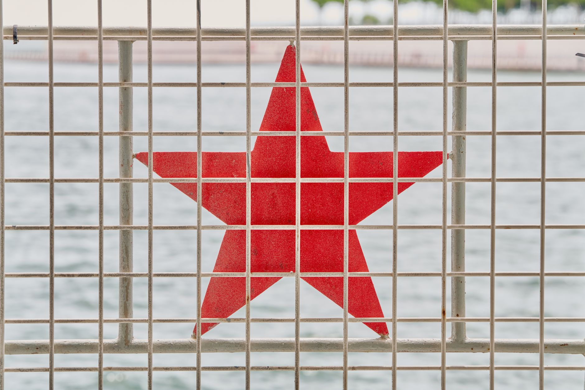 깨끗한 물의 시작: 정수기 설치, 스스로 혹은 전문가와 함께하는 방법 8 A red star symbol on a metal fence with a body of water in the background.