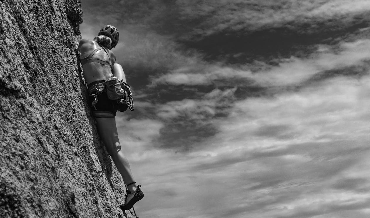 Woman Rock Climbing under Clouds in Black and White · Free Stock Photo