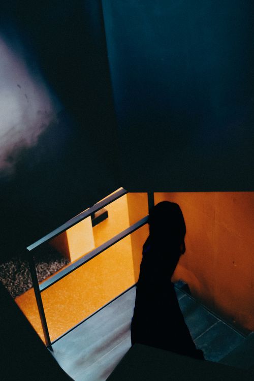 Free Silhouette descending a dimly lit staircase with contrasting dark and warm tones. Stock Photo