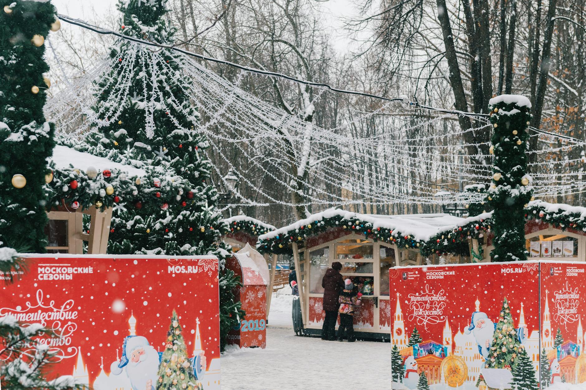 A snowy Christmas market scene with festive decorations and holiday stalls.