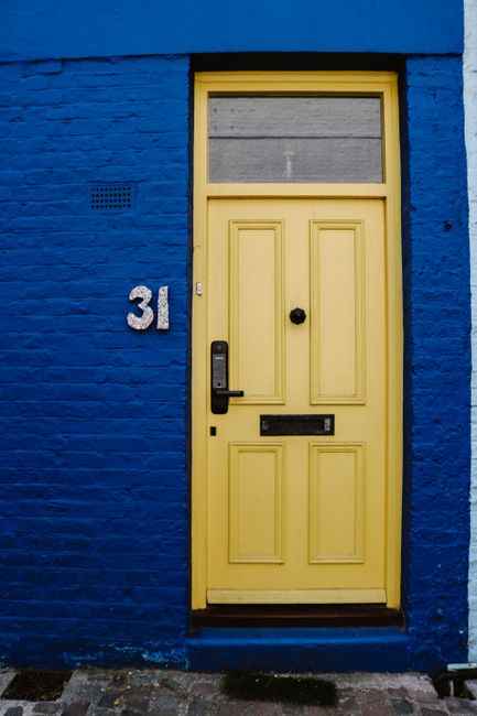 A visually striking yellow door set against a blue brick wall for urban design themes.