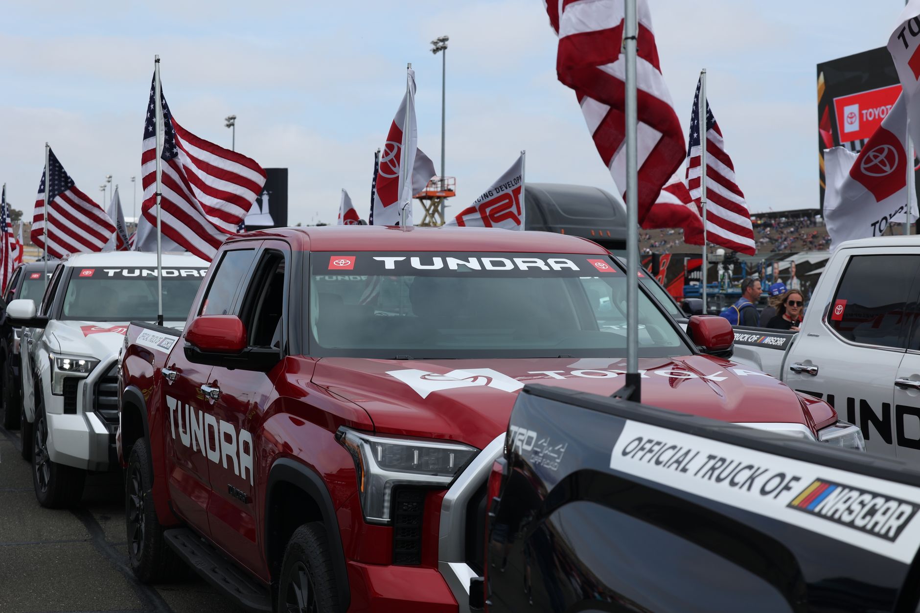 Toyota Tundra trucks in an American flag parade at a motorsport event.
