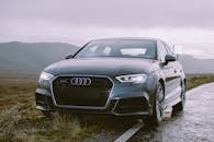 一辆优雅的灰色奥迪轿车停在风景优美的路边，展现了其豪华的设计