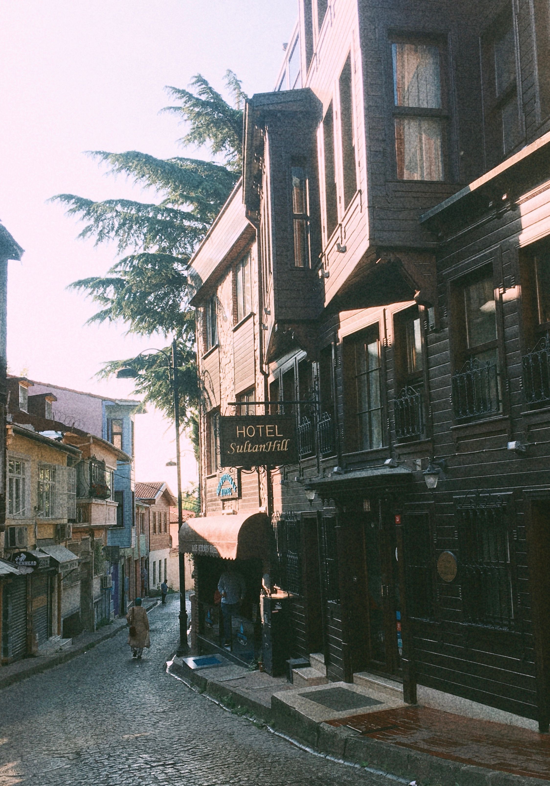 Cobblestone street in Istanbul with historic buildings and vibrant morning light.