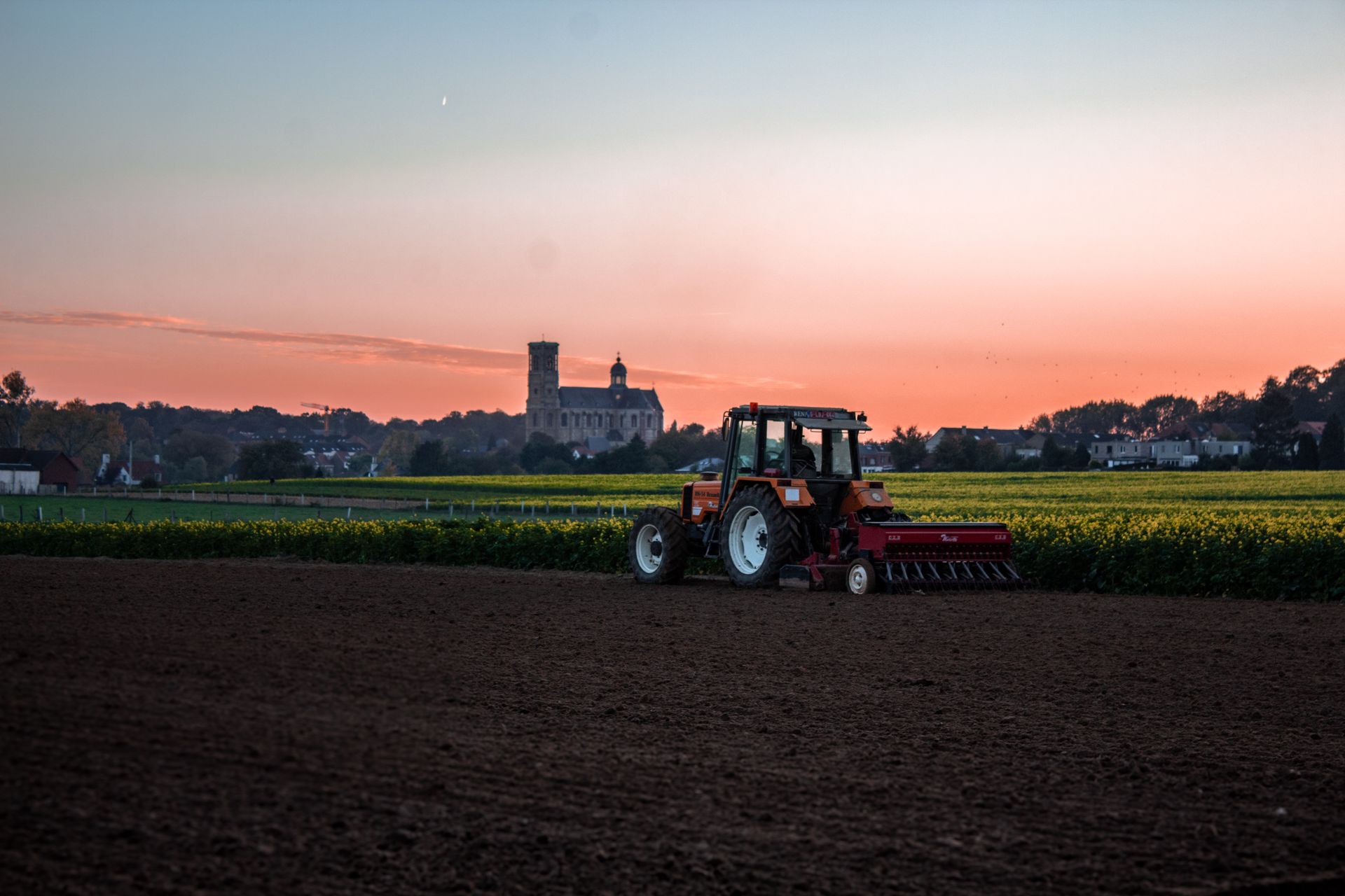 A tractor crossing dry fields at last light