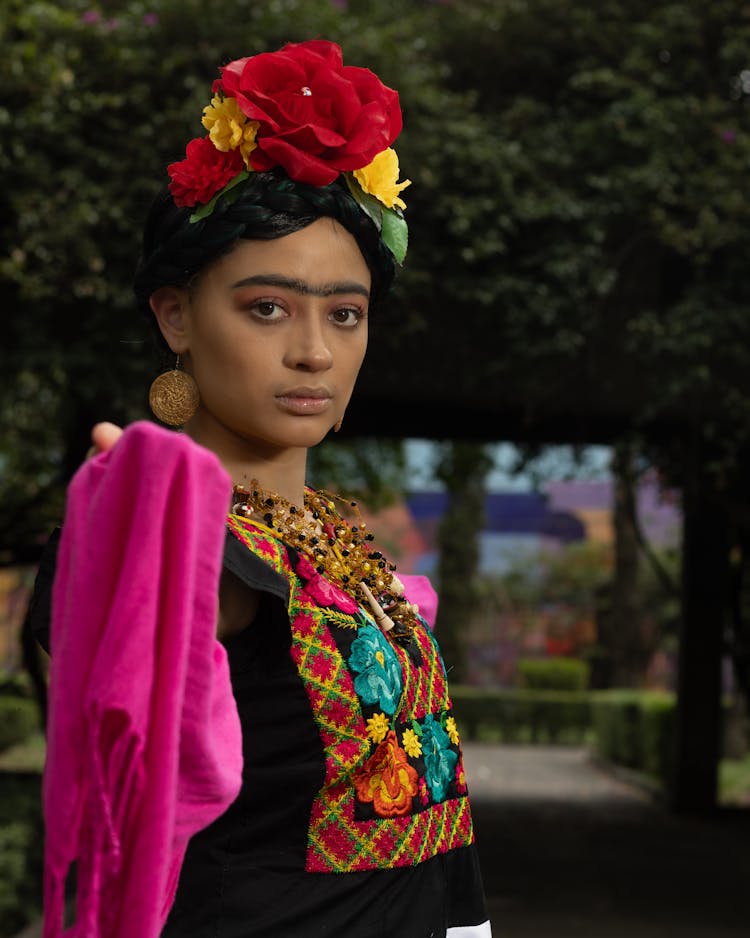 Young Woman In Bright Dress And Hair Decorated With Flowers Impersonating Frida Kahlo