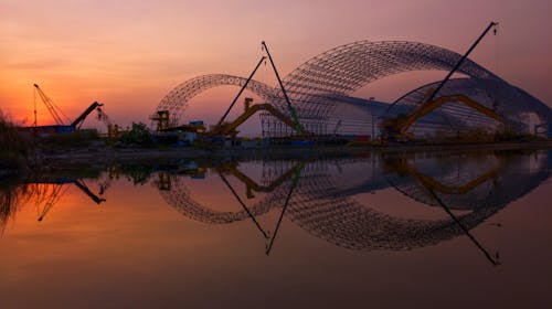 Building Construction and Machinery Reflection in Water at Sunset