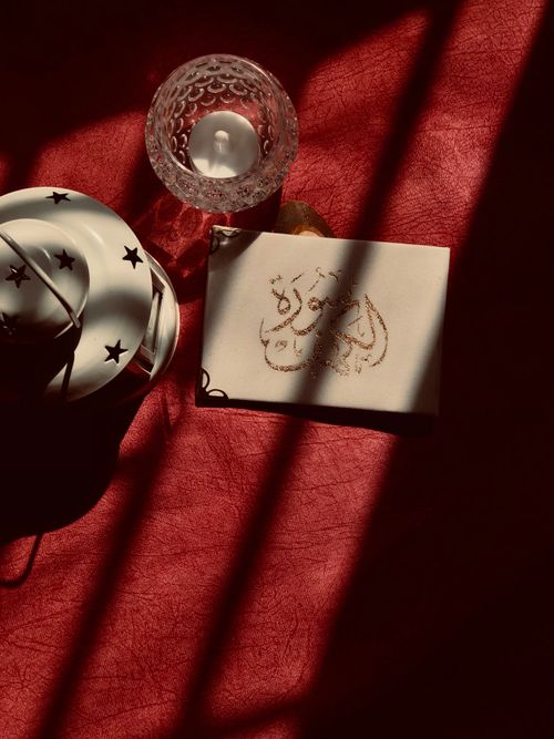 Free A captivating still life featuring a lantern, glass candle holder, and artistic shadows on a textured surface. Stock Photo