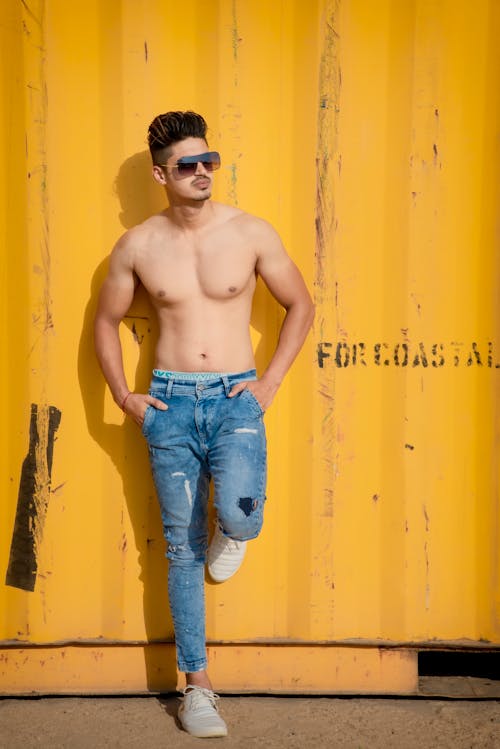 Young Shirtless Man Standing and Leaning against a Container in a Dock