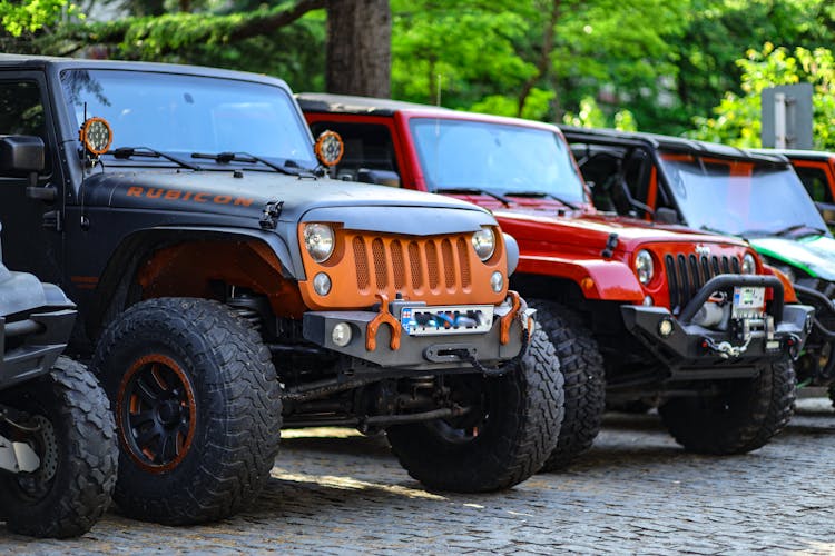 A Row Of Off Road Cars Parked On The Street 