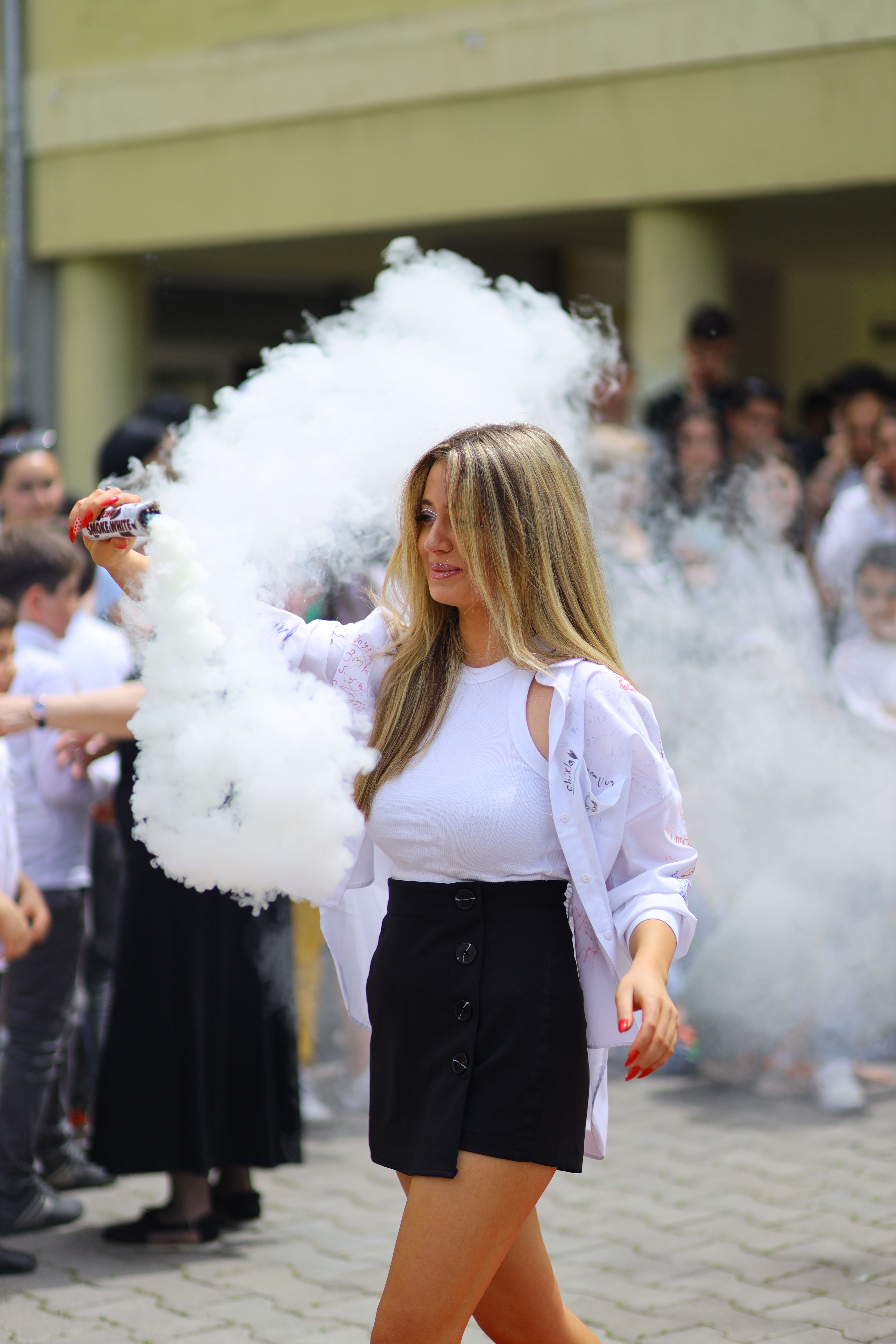 Young woman in a casual outfit waving a smoke flare during a street celebration in Georgia.