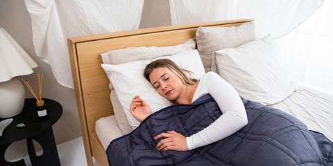 A woman asleep under a navy quilted weighted blanket