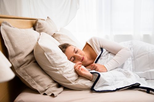 Free Caucasian woman peacefully sleeping in a cozy bed with pillows and duvet. Stock Photo