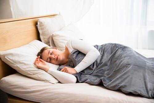 Free Young Woman Sleeping in Bed under a Duvet Stock Photo