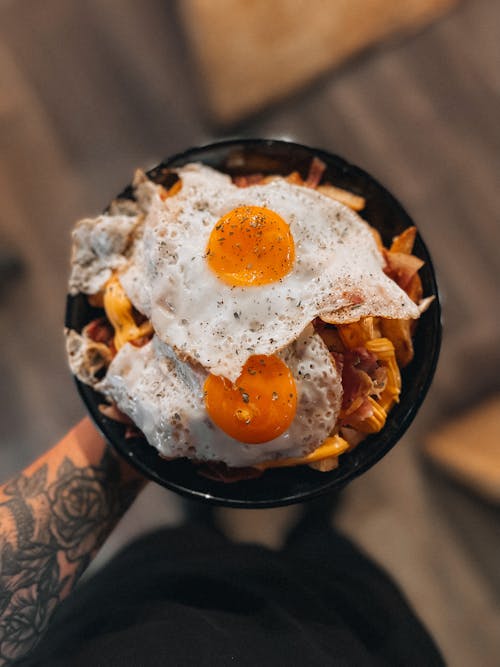 Hand Holding Fried Eggs with Pasta 