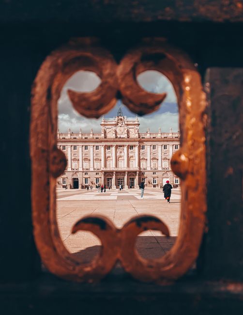 Baroque architecture of Royal Palace in Madrid seen through ornate gate.