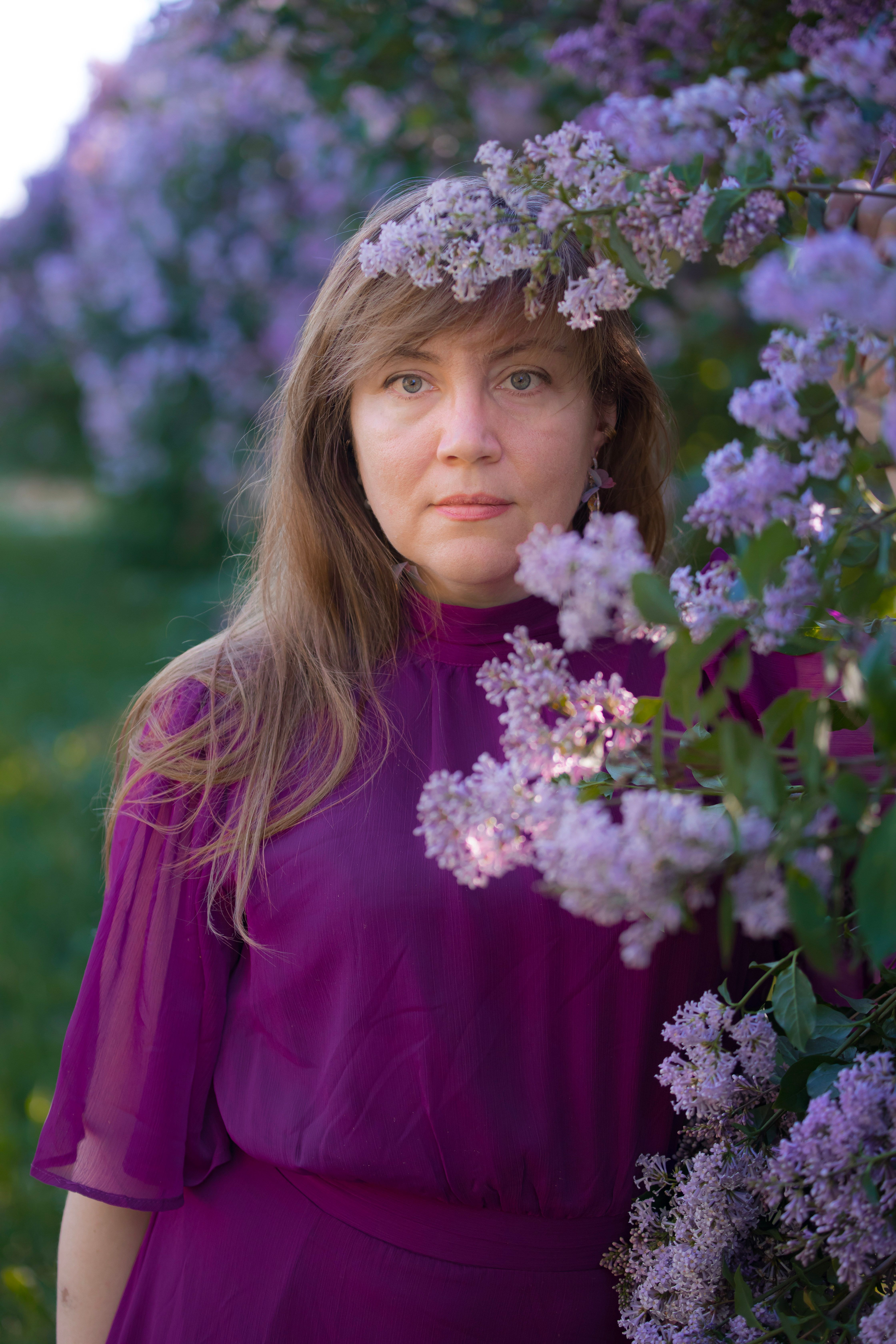 A woman in purple dress standing in front of purple flowers · Free ...