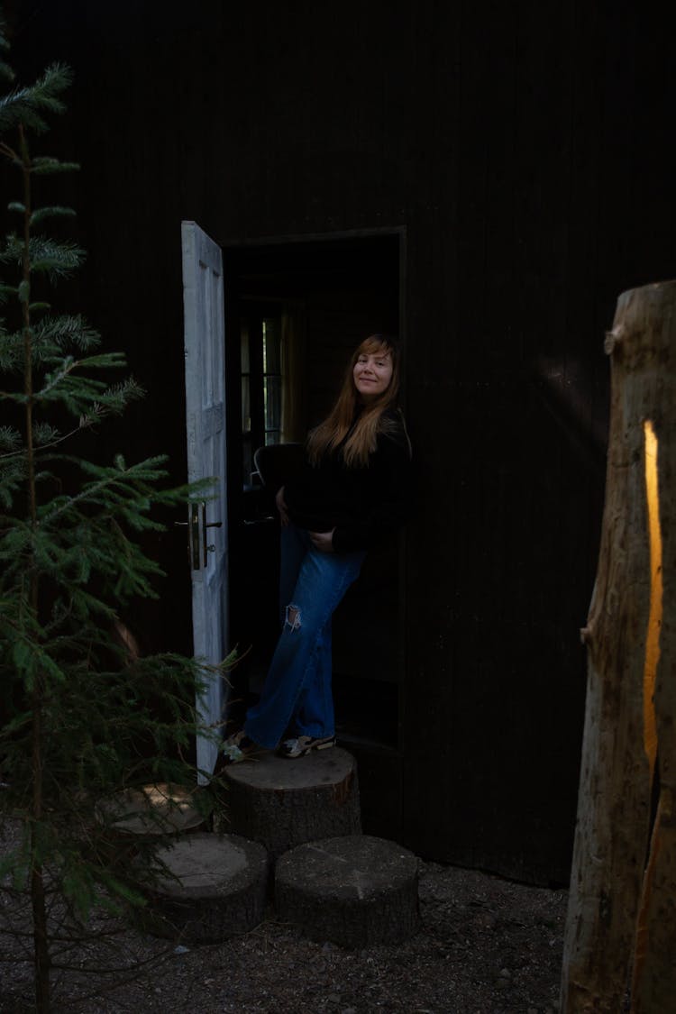 Woman Standing On Tree Trunks In Open Door